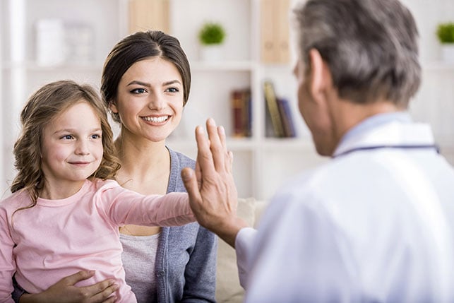 Doctor giving little girl a high five